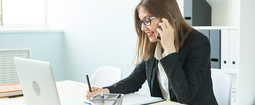 Como anunciar imóveis: corretora fala ao telefone enquanto escreve um documento