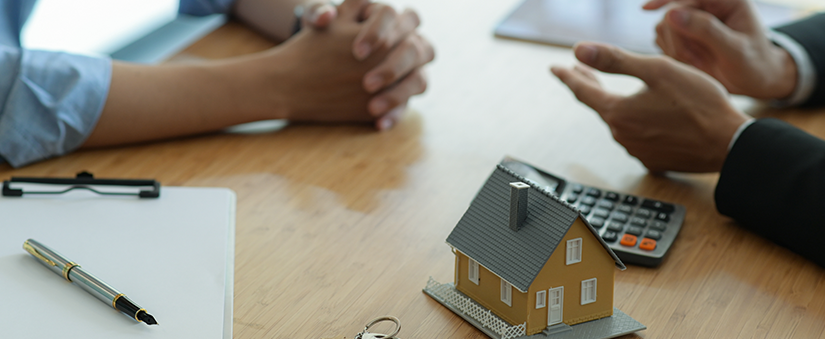 Anunciar em portais de imóveis - Mãos na mesa com miniatura de casa e calculadora