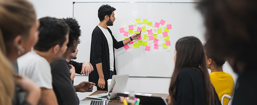 Pós-venda - Pessoas reunidas usando post-it em quadro