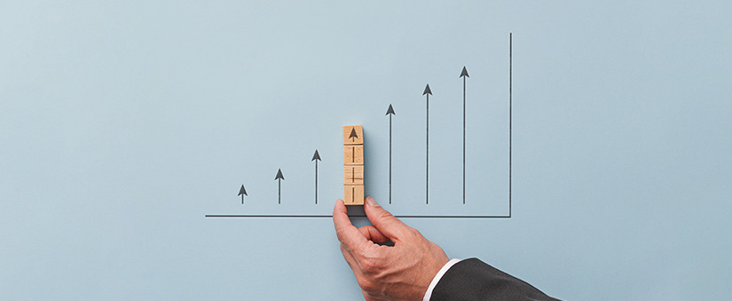 Indicadores imobiliários: mão segura seta num gráfico de setas que apontam para cima, indicando crescimento