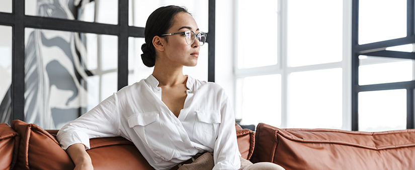 Dia da mulher: mulher de negócios contempla o horizonte sentada num sofá