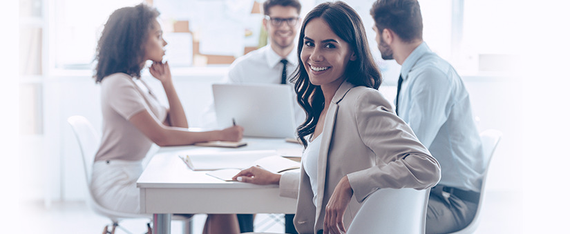 Mulher numa mesa com outras pessoas com notebooks ao redor