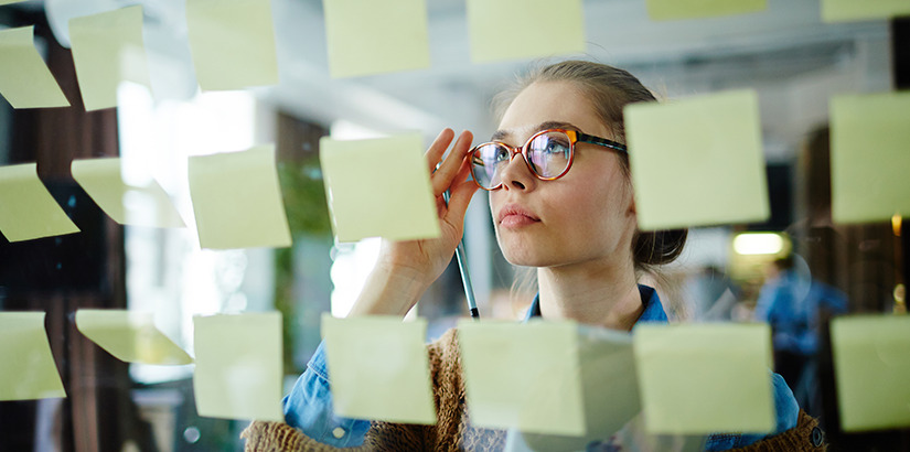 alto padrão: close em mulher olhando para uma parede de vidro com post-its colados