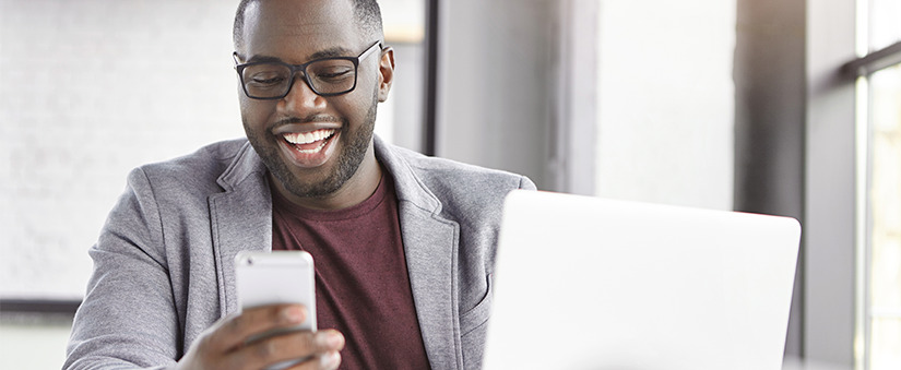 homem sorrindo olhando para um celular.