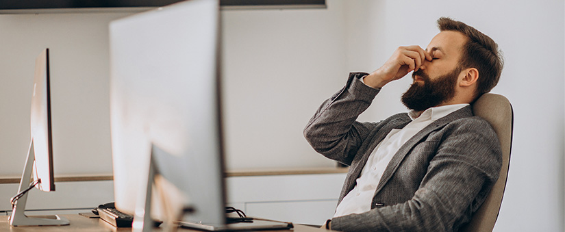 CRM do mercado imobiliário: homem sentado à frente de um computador, com a mão no rosto, demonstrando preocupação.