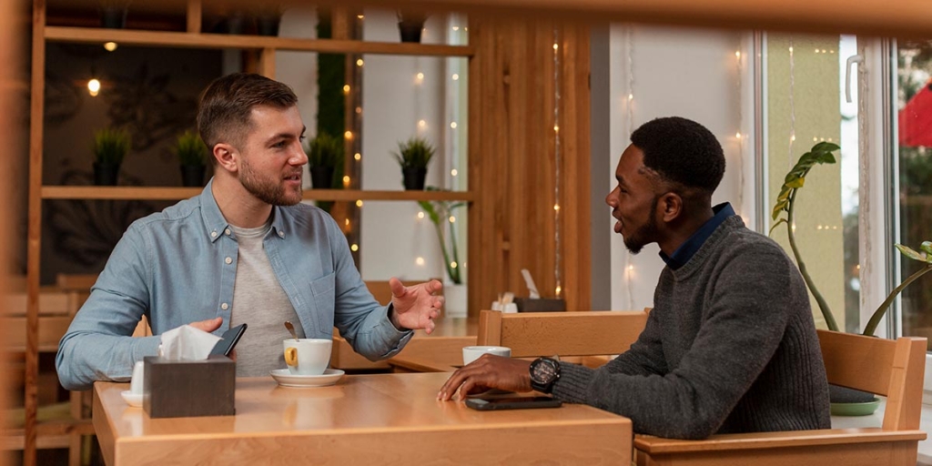 Pitch de vendas: dois homens conversando numa mesa num café. 