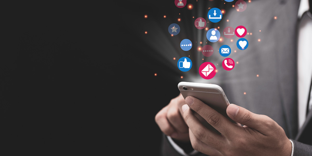 tecnologia persuasiva: close nas mãos de uma pessoa segurando um celular e, saindo da tela, alguns ícones que representam interações na internet.