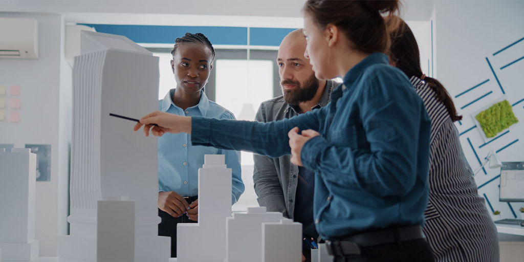 O que é eap: imagem de quatro pessoas olhando e analisando uma maquete com alguns edifícios,