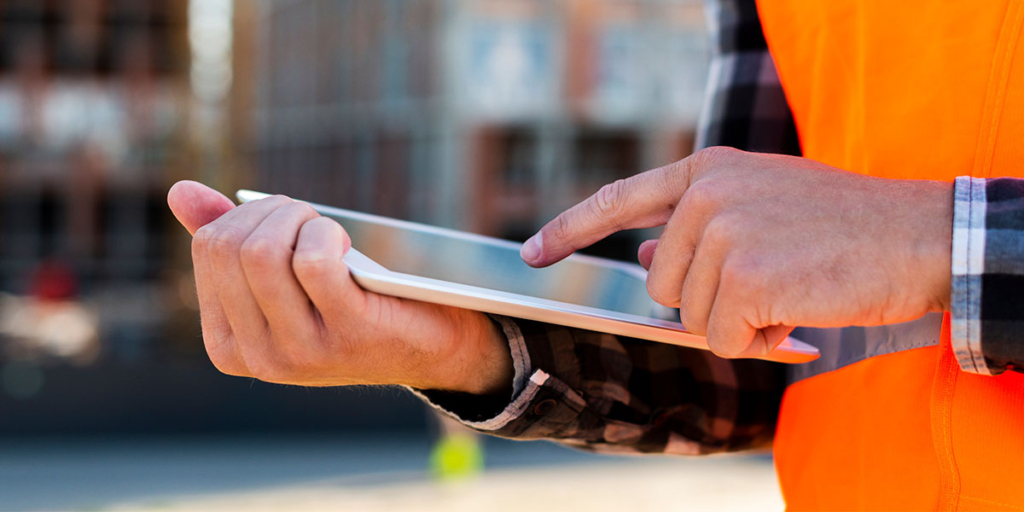 diário de obras: close nas mãos de uma pessoa segurando um tablet.