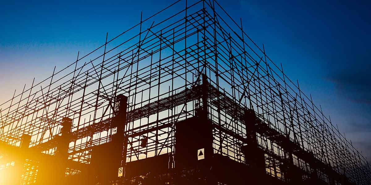 Construtoras no Brasil: foto de capa. Na imagem, vemos a silhoueta da estrutura de um prédio sendo construída ao fim do dia