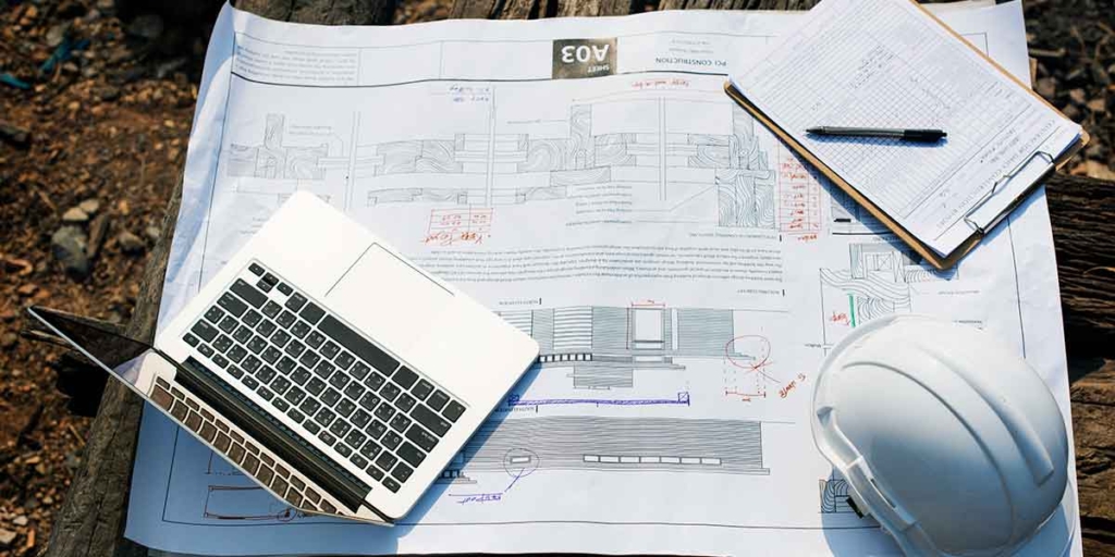 Como funciona o habita-se: imagem de uma mesa vista de cima com algumas plantas de imóveis e um notebook