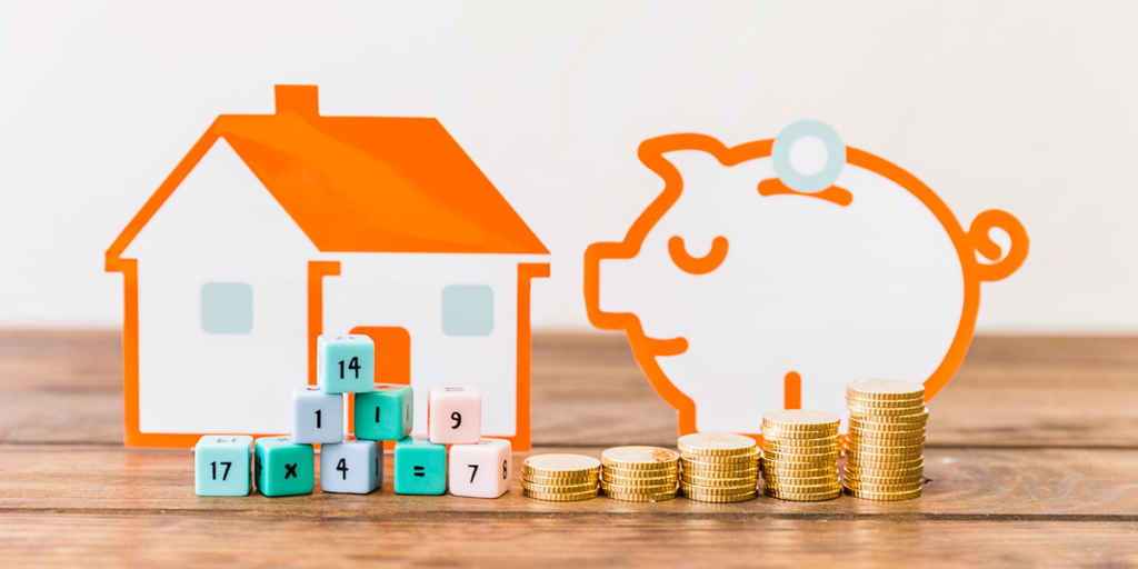 O que é INCC: ilustração de um cofre no formato de porco ao lado de uma casa em miniatura. Na frente algumas moedas empilhadas.