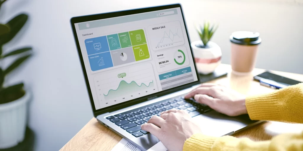 CRM Analítico: imagem de mãos de uma pessoa num notebook. Na tela, um dashboard com alguns dados.