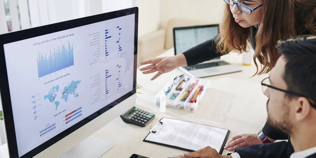 CRM Analítico: imagem de um homem e uma mulher em frente a um computador, olhando para um dashboard.
