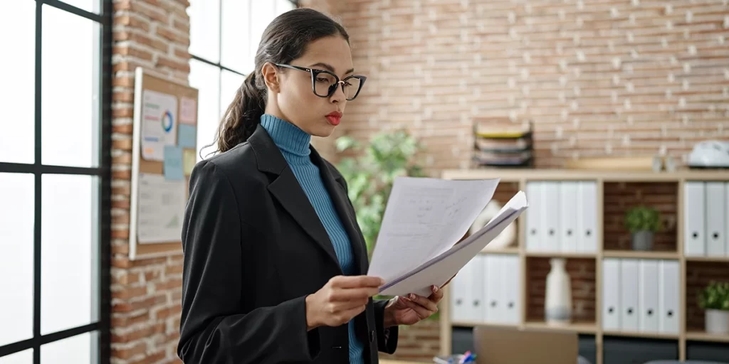 Documento de venda de imóvel: imagem de uma mulher segurando alguns papeis num escritório.
