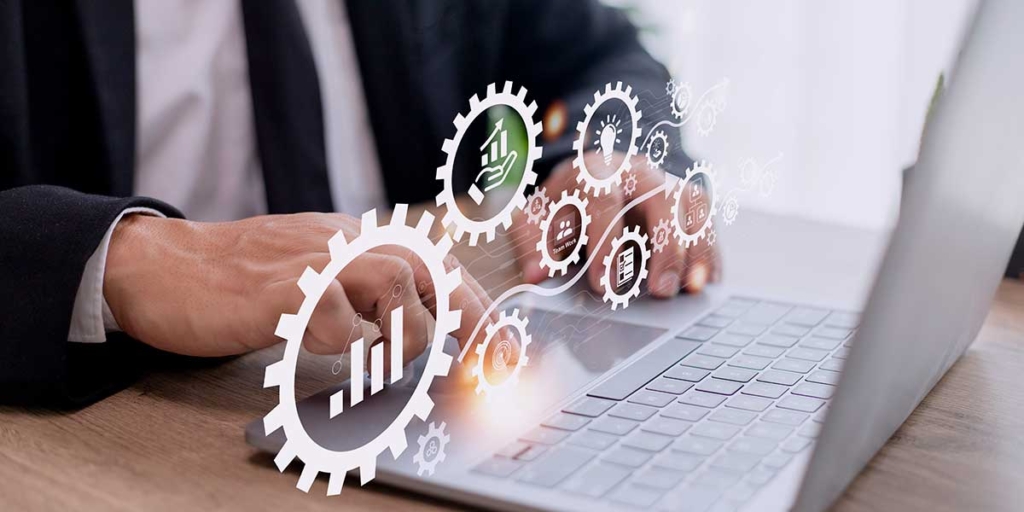 Escalabilidade de software: close nas mãos de uma pessoa digitando num notebook. Acima de suas mãos alguns ícones de gráficos.