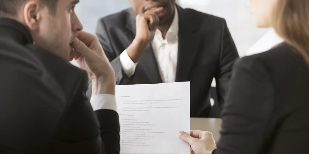 Distrato ou rescisão: três pessoas conversando. Uma delas segura um papel, que está em foco na imagem.