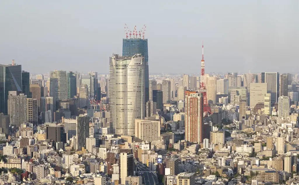 Urbanização e construção civil : A imagem mostra uma vista aérea de uma área urbana densa, possivelmente uma parte de uma cidade grande. Há uma variedade de edifícios de arquitetura moderna, com alguns edifícios de altura destacando-se na paisagem urbana. O céu está nublado, sugerindo um dia nublado ou comum. A imagem captura a densidade e a complexidade de uma cidade grande, com suas estruturas arquitetônicas e o espaço entre elas.