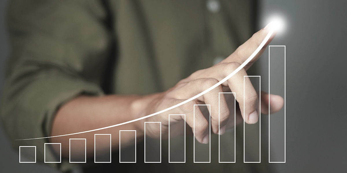 indicadores de desempenho: imagem de uma mão apontando para a ilustração de um gráfico em destaque na tela. É um gráfico de barras crescente com uma seta para cima.