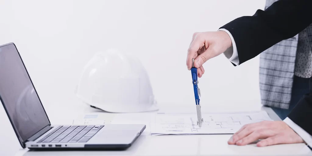 aprovação de projeto na prefeitura:  Imagem de um homem em traje e gravata segurando uma caneta e olhando para um laptop na mesa. O laptop parece estar aberto e o homem está segurando uma folha de papel com um plano em azul. O fundo parece ser um espaço de escritório branco e azul com uma janela no fundo. A imagem está bem iluminada e as cores são vibrantes. A atmosfera geral da imagem é profissional e concentrada.